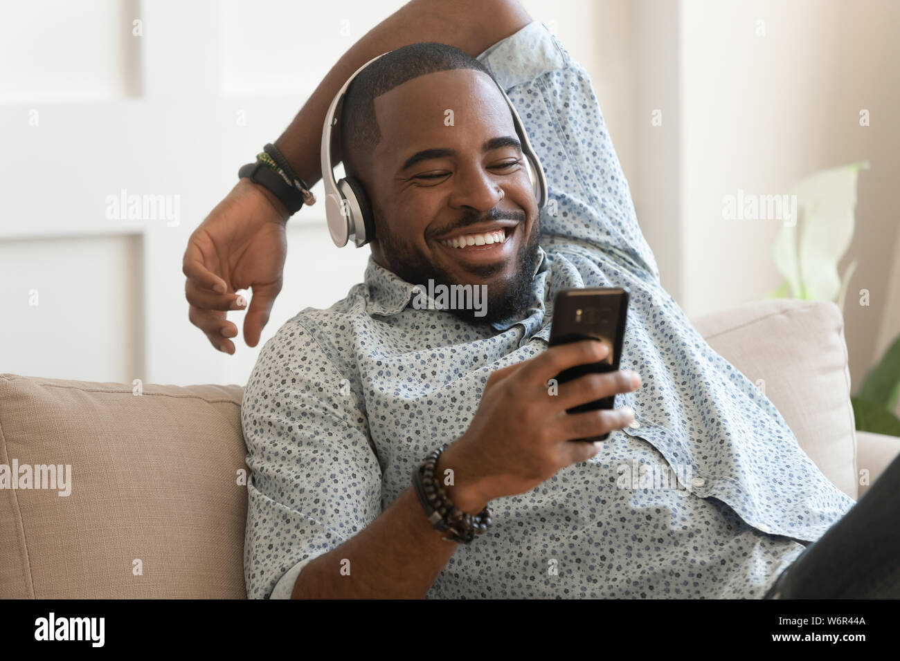 Lächelnden jungen afrikanischen Mann mit Kopfhörern auf mobile Musik hören Stockfoto