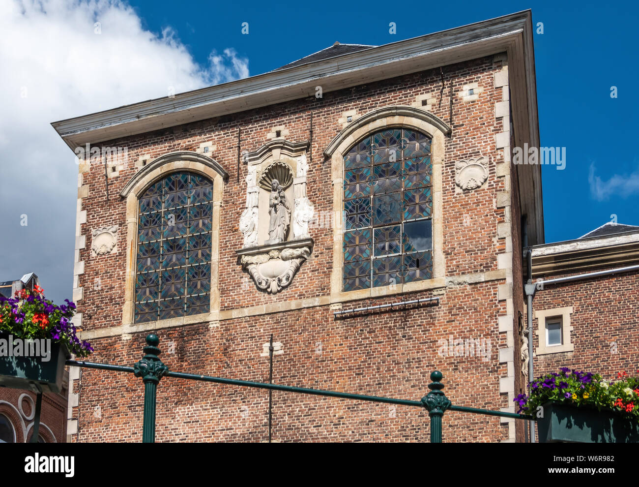 Gent, Flandern, Belgien - 21. Juni 2019: roten Backsteinfassade mit Zentral weiße Madonna Statue des Heiligen Augustinus Kreuzgang unter blauem Himmel entlang Stockfoto