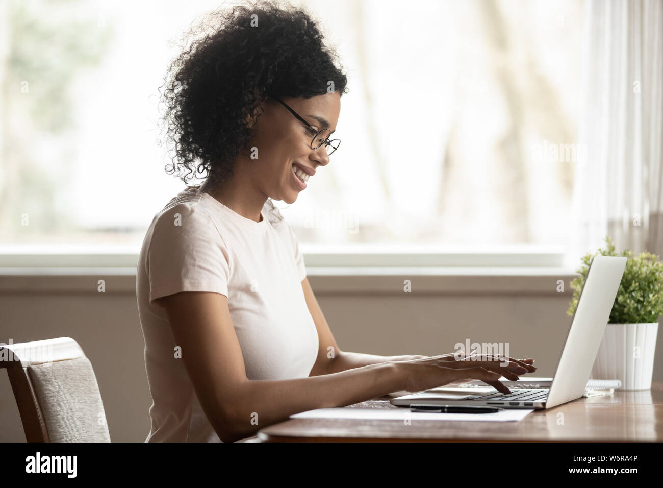 Afrikanische Frau am Tisch sitzend Arbeiten am Computer zu Hause. Stockfoto