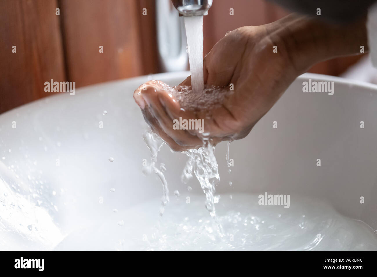 Detailansicht afrikanische Mann Hand sammeln Wasser gießen von Hahn Stockfoto