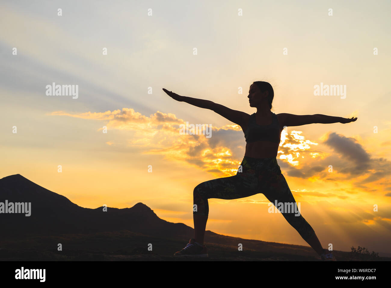 Silhouette der jungen Frau Üben Yoga oder pilates bei Sonnenuntergang oder Sunrise in wunderschöner Lage, ausfallschritt Übung, stehend im Krieger Stockfoto