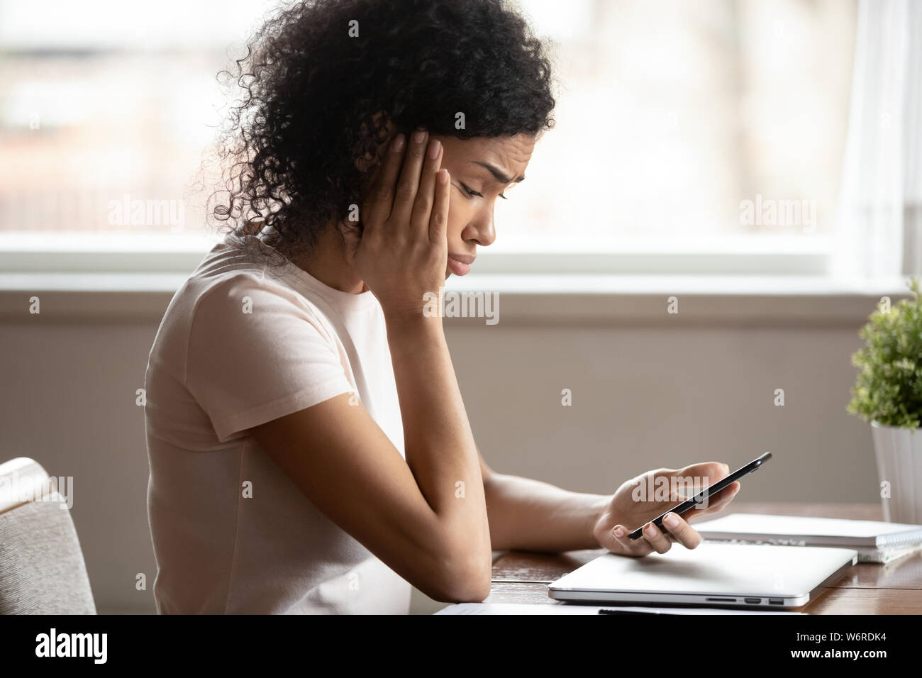 Afrikanische Frau am Handy Bildschirm schaut verärgert fühlt Stockfoto