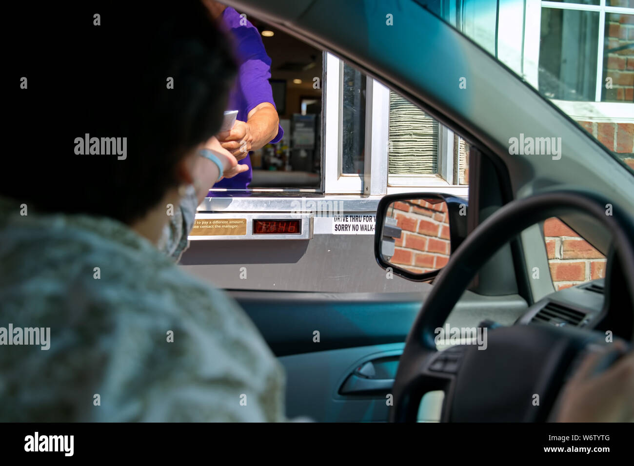 Fast food von Mitarbeitern und Kunden die Hände in einer Transaktion an der Drive Thru. Stockfoto