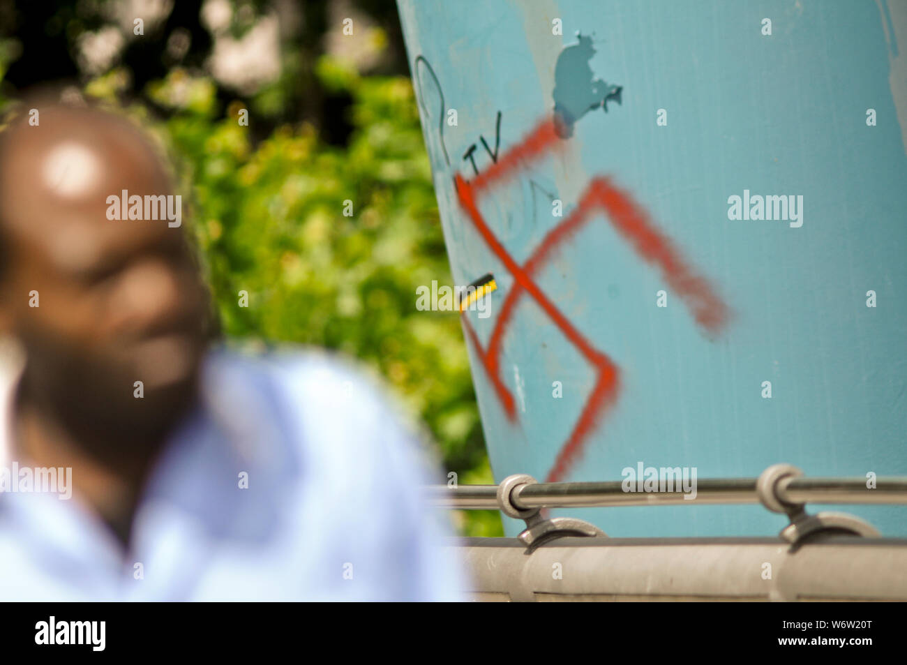 Ein schwarzer Mann zu Fuß durch ein Hakenkreuz auf einer Brücke Spalte gemalt. Frankfurt, Main. Deutschland Stockfoto