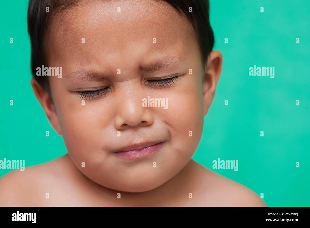 Kleinkind alter Junge, die Anzeichen von leichten Schmerzen mit geschlossenen Augen und Gesicht die Stirn runzeln. Stockfoto
