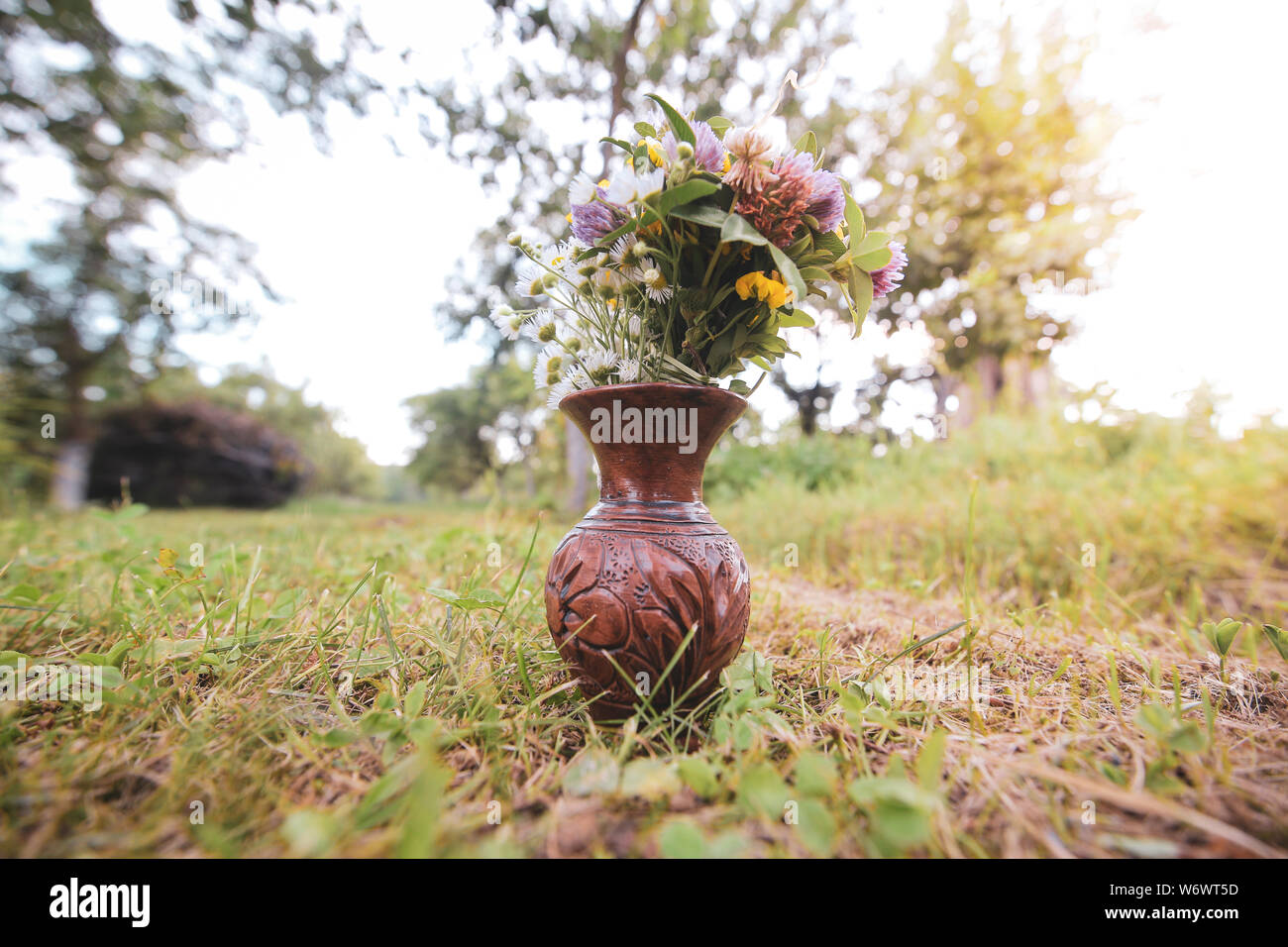Bouquet of colorful wild wild flowers in a broken clay pot laid on the grass Stockfoto