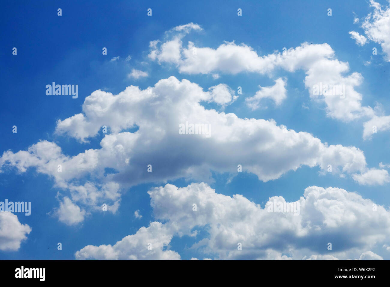 Flauschige weiße Wolken schweben über dem blauen Sommerhimmel Stockfoto