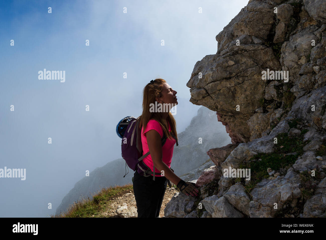 Frau Wanderer küssen eine Felswand in den Julischen Alpen, Slowenien, gerade unter Mangart Peak, nach dem Abstieg der Klettersteig Route. Misty Wolken im Bac Stockfoto