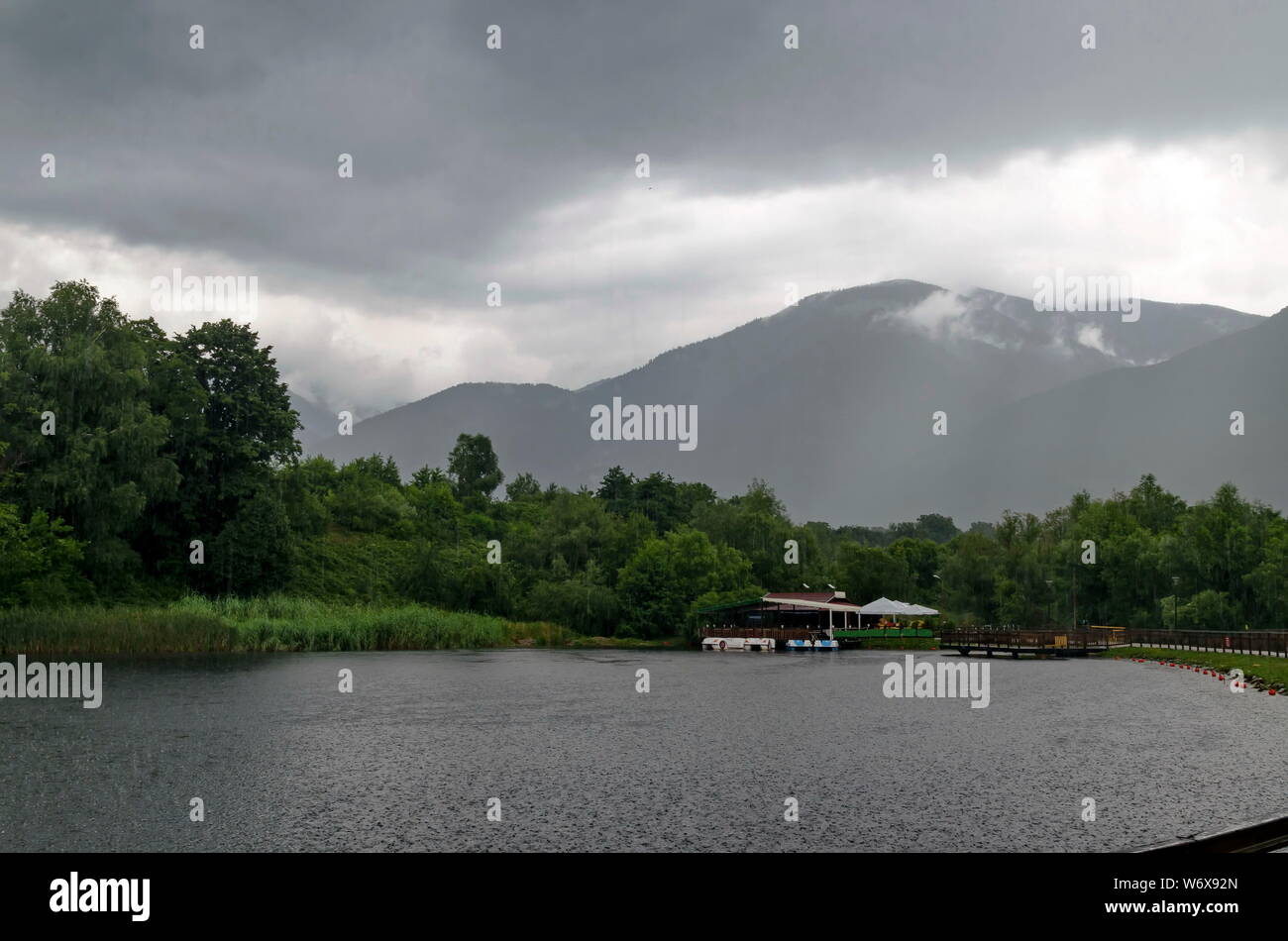 Ein Blick auf den künstlichen See mit Shelter und Boote an einem regnerischen Tag in rila Park in der Nähe der Stadt Sliven, Bulgarien Stockfoto