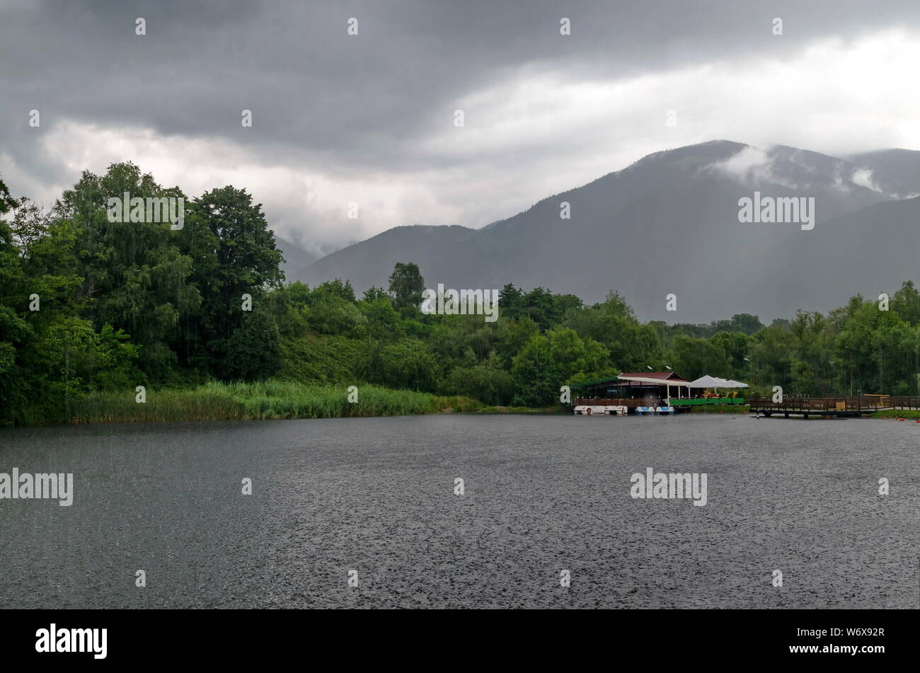 Ein Blick auf den künstlichen See mit Shelter und Boote an einem regnerischen Tag in rila Park in der Nähe der Stadt Sliven, Bulgarien Stockfoto