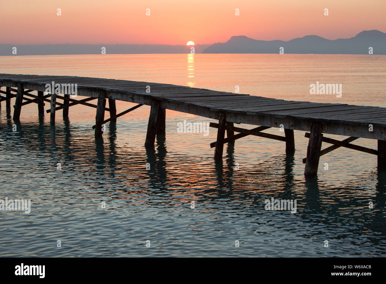 Sonnenaufgang am langen holzsteg an der Playa de Muro in der Bucht von Alcudia, Europa, Spanien, Mallorca, Norden, Sonne ist das Küssen das Meer Stockfoto