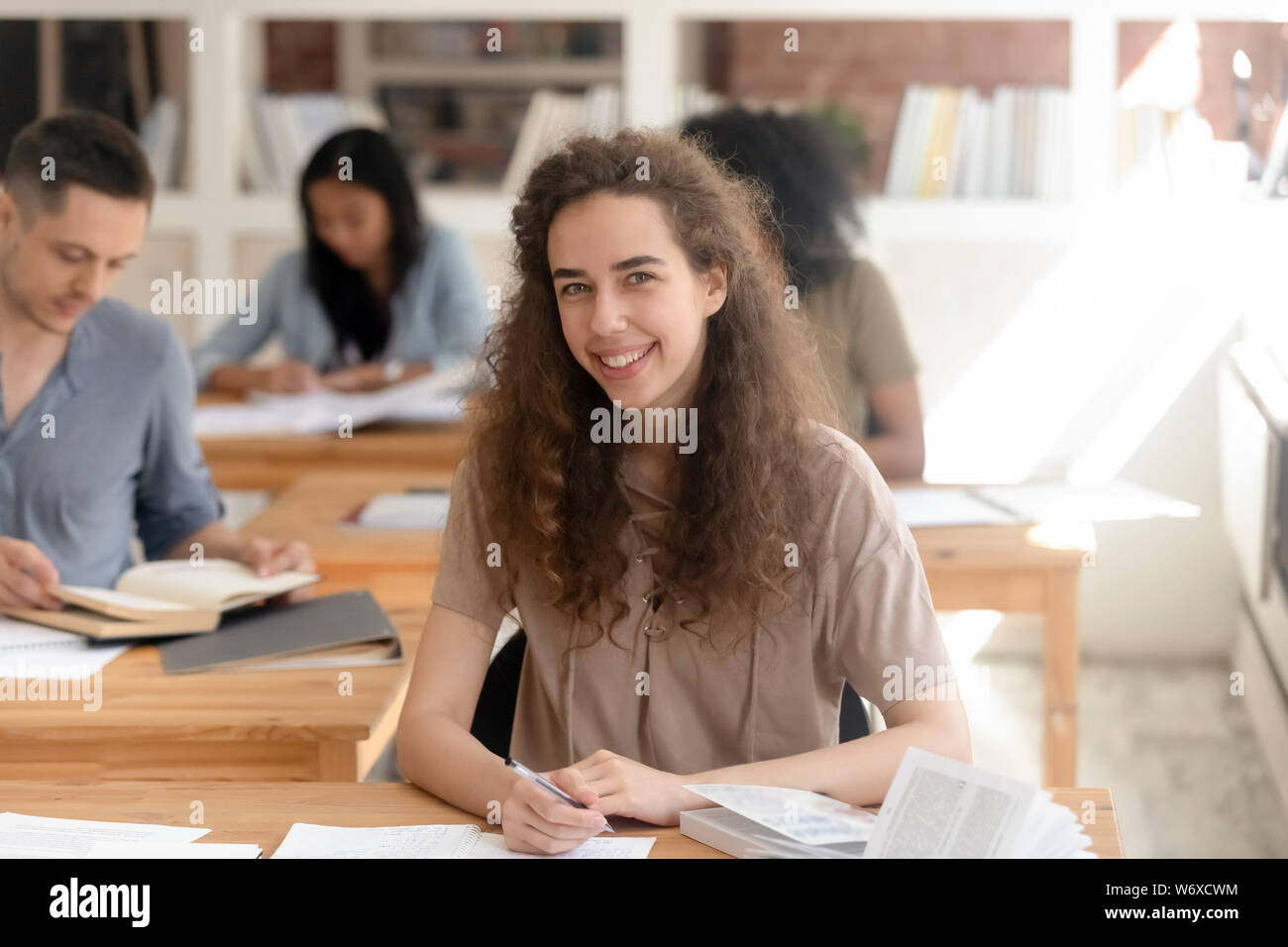 Erfolgreiche Studenten sitzen am Schreibtisch mit Blick auf die Kamera Stockfoto