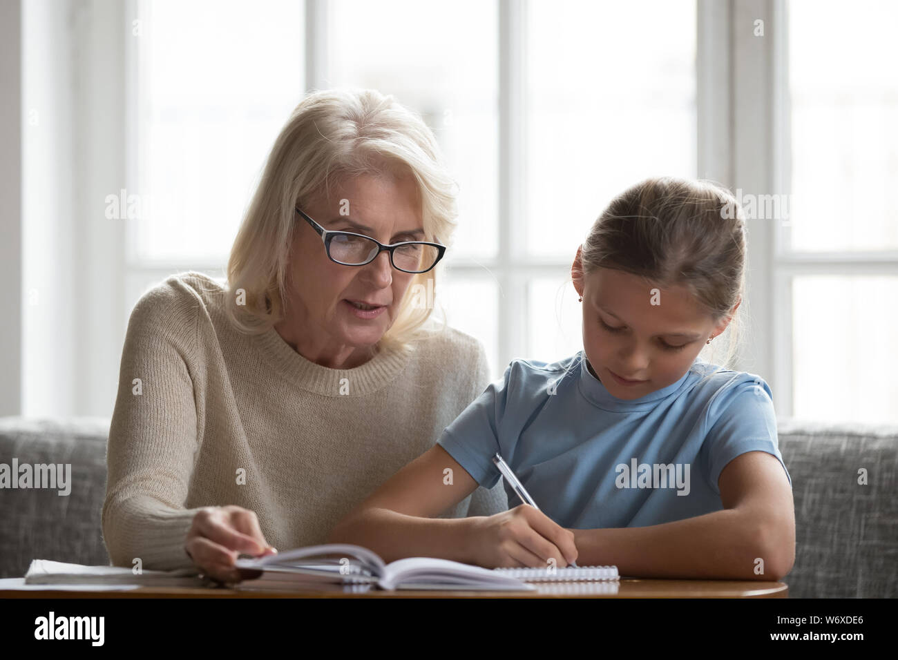 Ältere Tutor hilft Schule Kind Mädchen mit Hausaufgaben Stockfoto