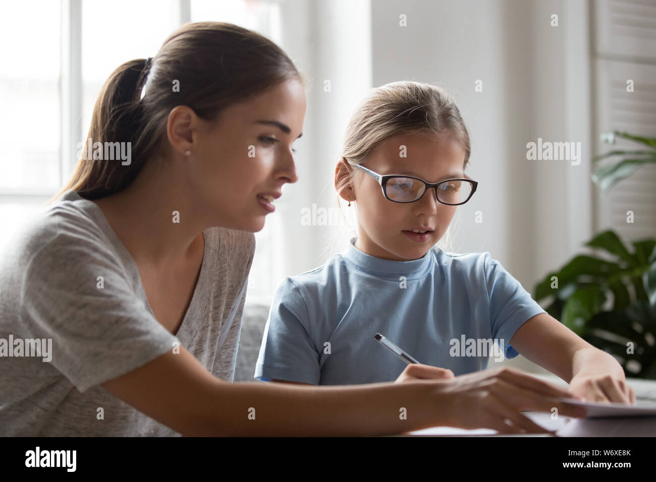 Mutter hilft mit Schule Aufgabe Hausaufgaben kleine Tochter Stockfoto