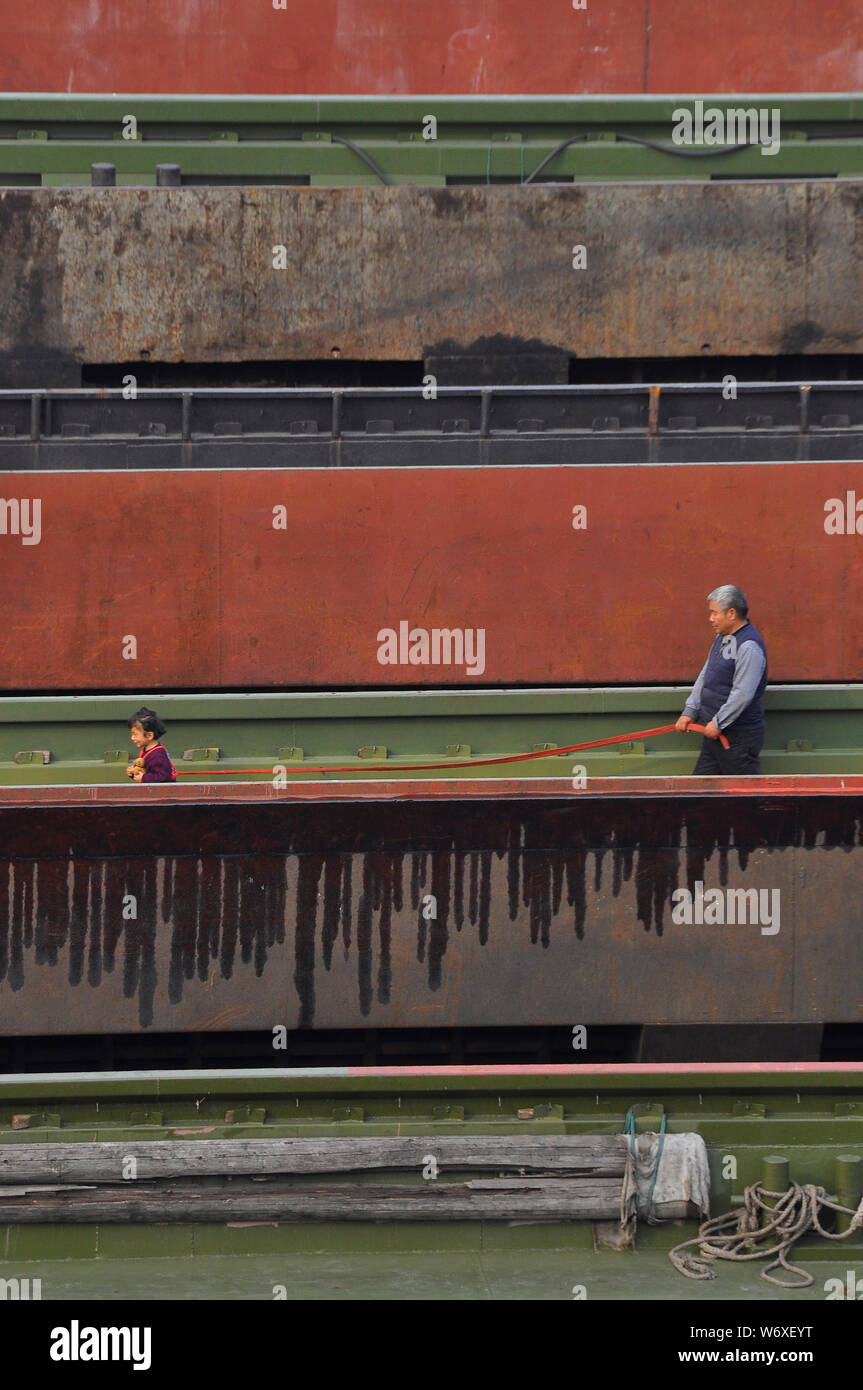 Ein großväter nimmt seine Enkelin für einen Spaziergang an der Leine an einem Kanal Boot auf dem Jangtse Fluss, Nantong China Stockfoto