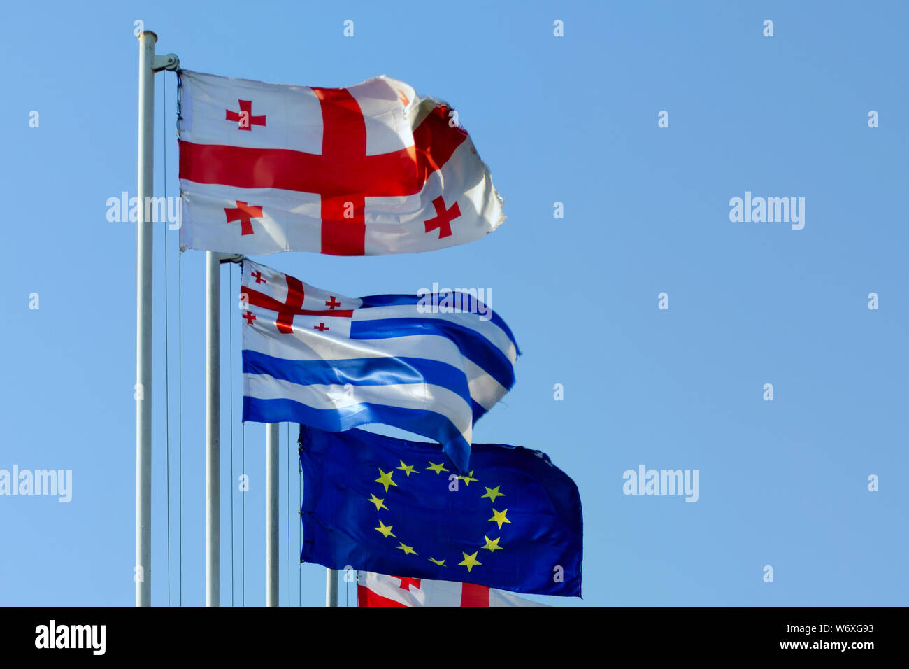Flagge von Georgia, Adscharien und der Europäischen Union, die im Wind flattern vor blauem Himmel. Stockfoto