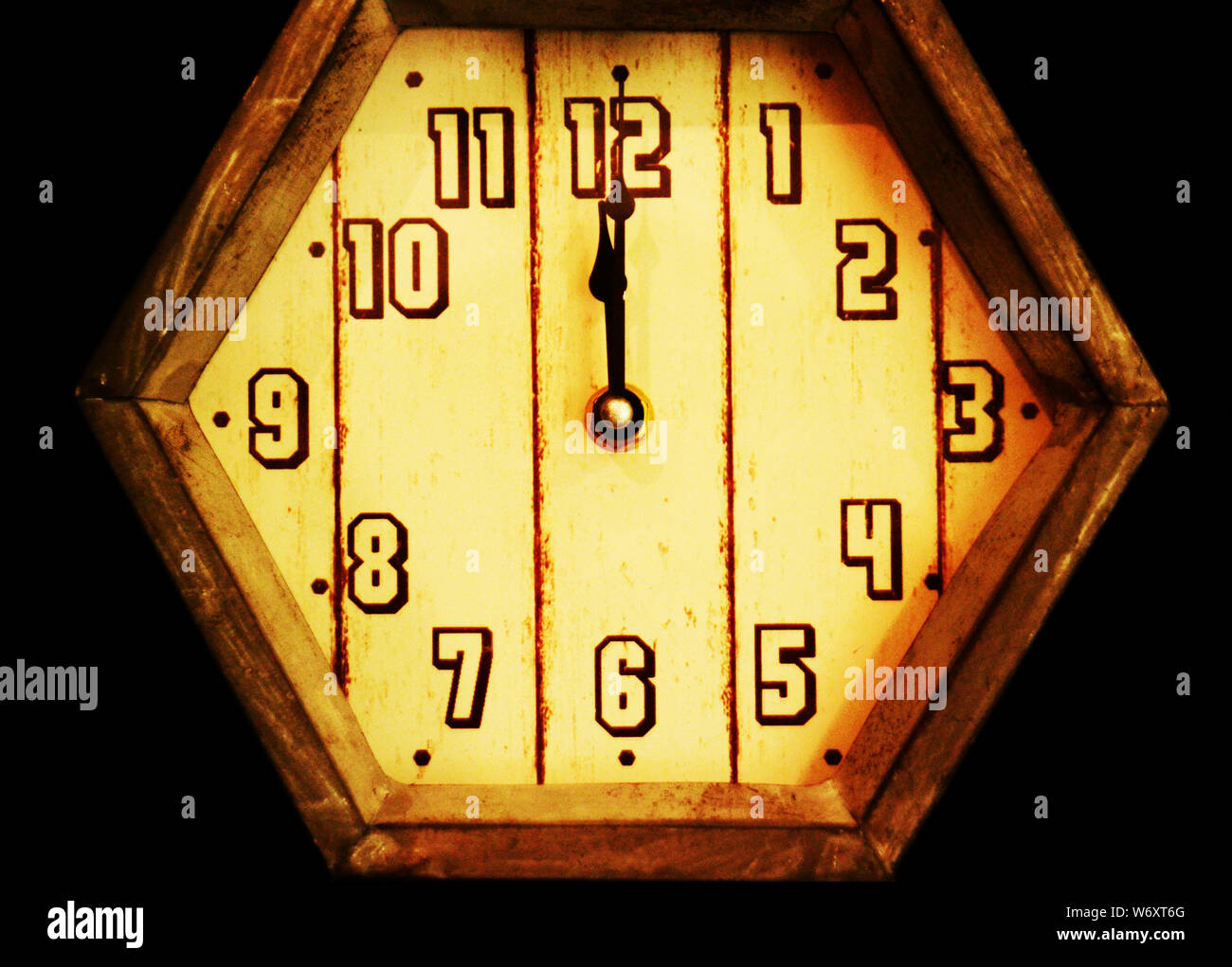 Mitternacht: Eine alte Holzuhr im Retro-Stil, die kurz nach Mitternacht steht, ist in einem schwarzen leeren Raum zu sehen. Stockfoto