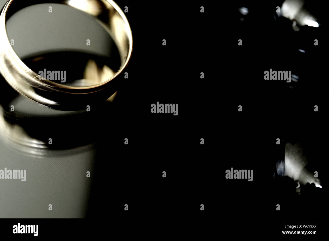 Erzengel: Ein goldener Ring dreht sich mit hoher Geschwindigkeit auf einer reflektierenden Oberfläche, die von schwarzen Felsen umgeben ist. Stockfoto