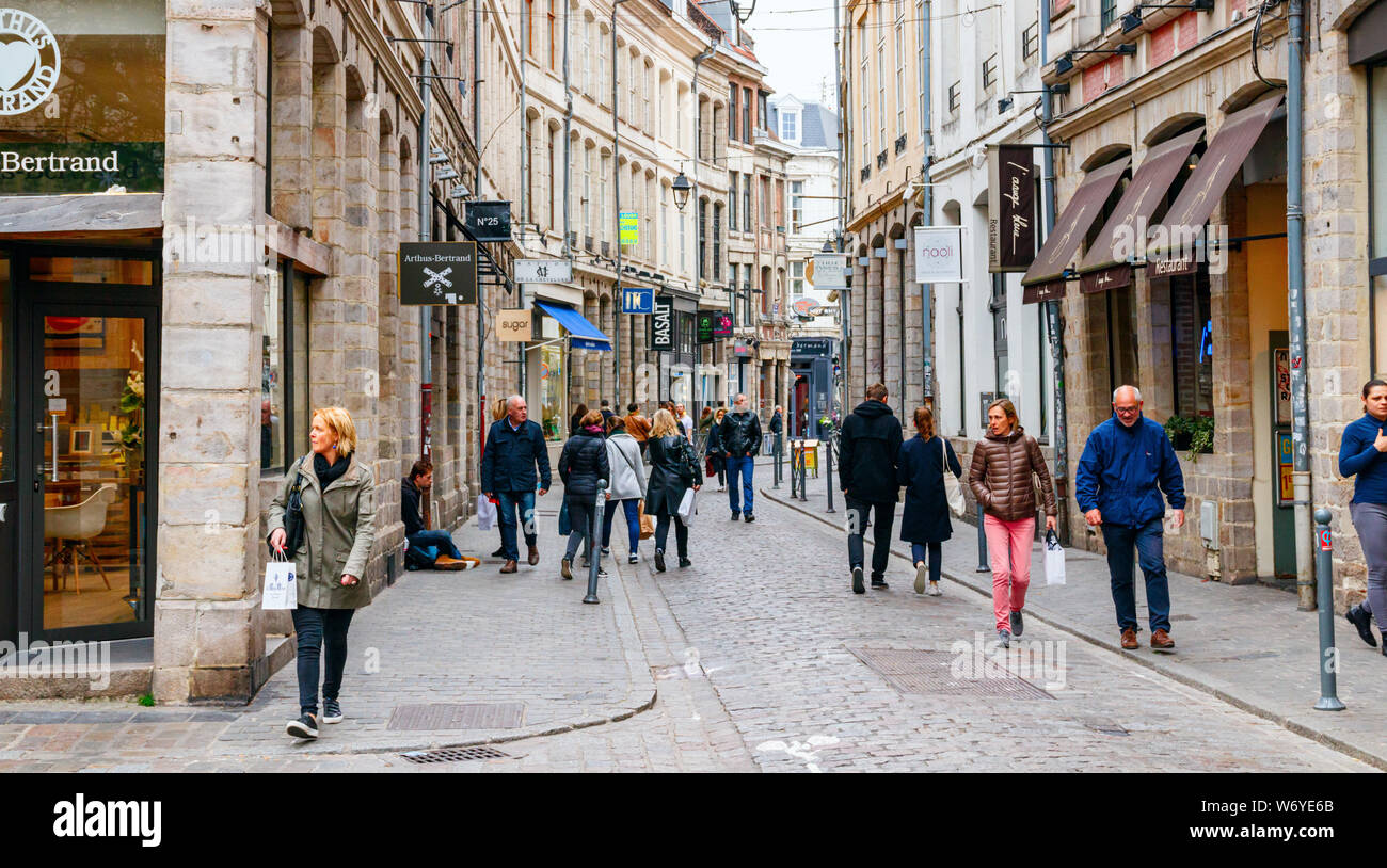 Rue Lepelletier mit Geschäften und Menschen zu Fuß entlang der Straße an einem bewölkten Nachmittag. Die Straße ist Teil der Vieux-Lille. Lille, Frankreich. Stockfoto