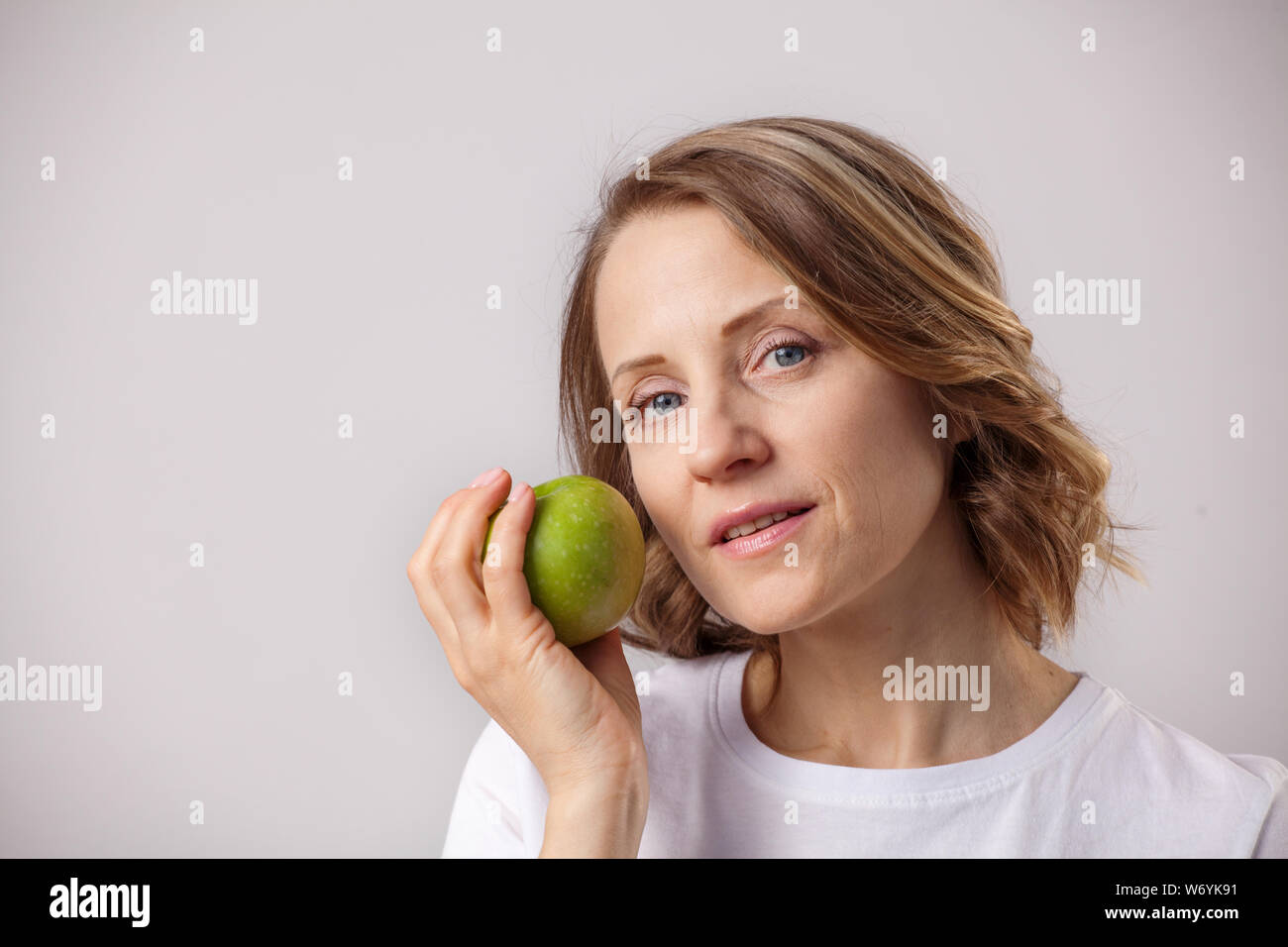 Lächelnd schöne Frau mit einem Apple auf grauem Hintergrund Stockfoto