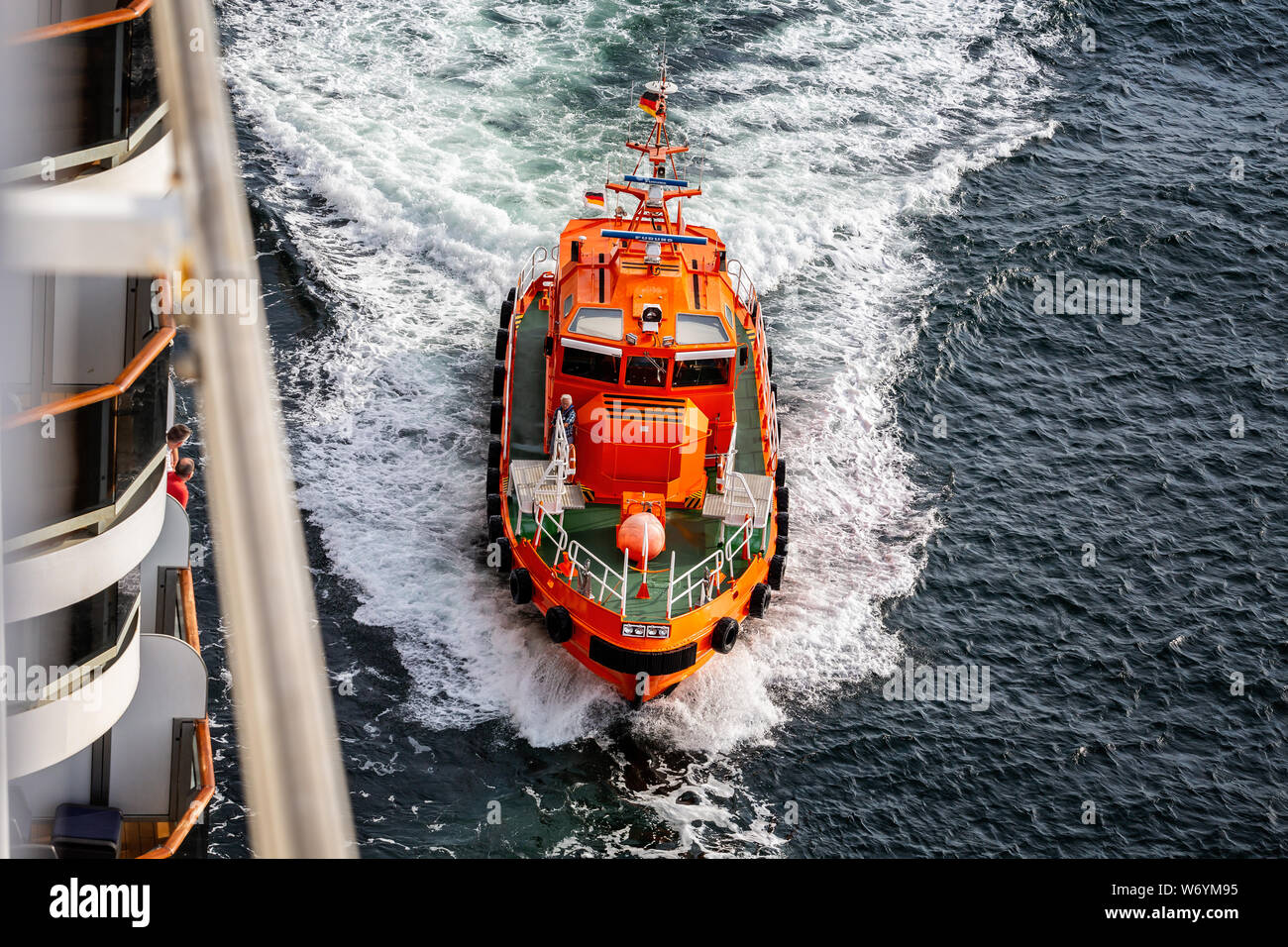 Deutsche Pilot Boot ziehen Zusammenarbeit mit einem Kreuzfahrtschiff an Geschwindigkeit auf See in der Nähe von Kiel, Deutschland 0 n vom 25. Juli 2019 Stockfoto