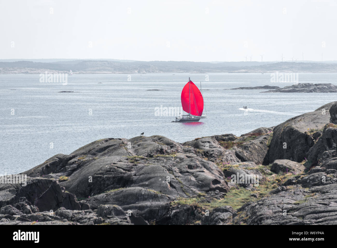 Ursholmen, Schweden - Juli 26, 2019: Blick auf ein Segelschiff mit einem roten Segel vor der Insel Ursholmen in der schwedischen Kosterhavet Nationalpark im Westen Stockfoto