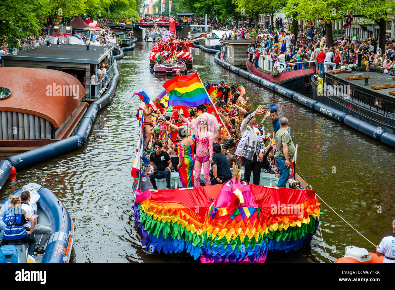 Eine Gruppe von Menschen auf einem Boot mit einem Regenbogen während der Parade eingerichtet. Die Canal Parade ist, was Amsterdam Gay Pride berühmt ist. Es ist die Krone auf Ihre zwei Wochen fest, dass mehr als 200 Veranstaltungen bietet. Die Boote starten im Scheepvaart Museum auf dem östlichen Teil der Innenstadt in Richtung Amstel Fluß. Die Schwimmer von dort weiter unter Berücksichtigung der Prinsengracht zur Westerdok. Der Canal Parade beginnt um 12.30 Uhr und dauert den ganzen Nachmittag. Rund 80 Boote verschiedener Organisationen und gemeinnützige Organisationen beteiligen sich an der Veranstaltung. Stockfoto