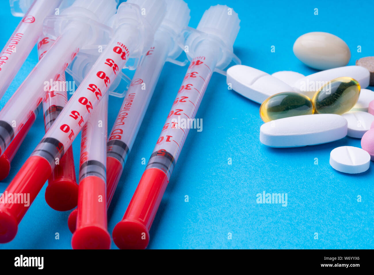 1 ml Insulin spritzen und rosa Pillen auf einem blauen Hintergrund. Omega 3 Stockfoto