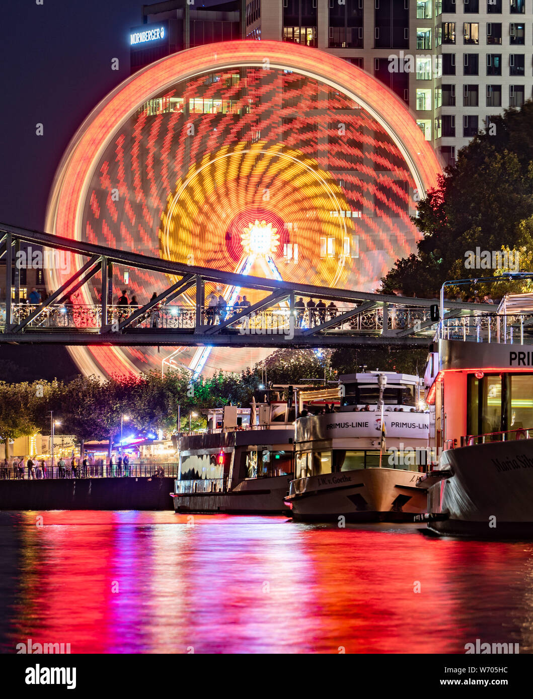 03.August 2019 Hessen, Frankfurt/Main: ein Riesenrad dreht sich am Ufer des Main, während die Lichter der Mainfest in den Fluss vor der Ausflugsschiffe (Foto mit langen Belichtungszeiten) reflektiert werden. Nach Angaben der Stadt, die Folk Festival, das erste im Jahr 1340 gefeiert wurde zu weihen, in der Nähe der Dreikönigskirche (Kirche der Heiligen Drei Könige), war ursprünglich eine Rettungsleine, die von Fischern und Seglern an den Main. Es findet vom 2. August bis zum 5. August 2019. Foto: Frank Rumpenhorst/dpa Stockfoto