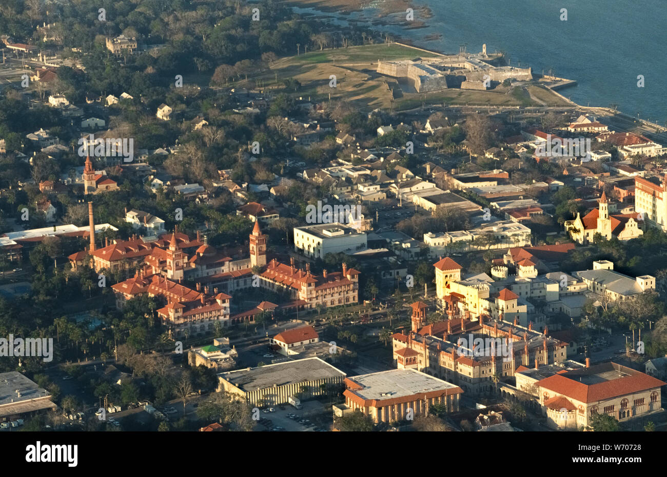 Die Sonne untergegangen war, wenn diese Luftaufnahme der historischen St. Augustine an der Ostküste von Florida, USA aufgenommen wurde. Die weitläufige red-roofed Gebäude mit Twin Towers (links Mitte) ist die Heimat von Flagler College, ein vier Jahre Liberal Arts College, die ursprünglich war der Ponce de Leon Hotel, ein luxuriöses Resort von Amerikanischen industriellen Henry Flagler wurde im Jahre 1888 erbaut. Die COQUINA - Stein Festung (hinten rechts) ist das Castillo de San Marcos, mit Blick auf die Bucht von mantanzas und Termine bis 1672. St. Augustine Ansprüche Amerikas älteste kontinuierlich bewohnte Stadt werden seit ihrer Gründung als spanische Territorium im Jahre 1565. Stockfoto