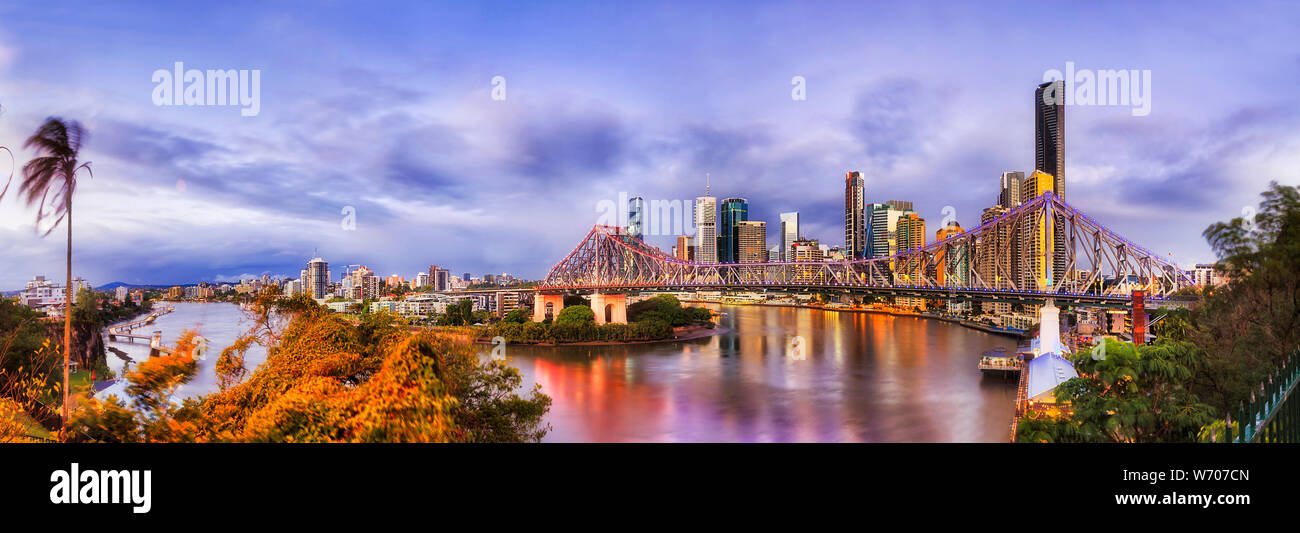 Sunrise Panorama der Innenstadt von Brisbane CBD Wahrzeichen und hoch aufragenden Türmen hinter der Story Bridge in Brisbane River mit leuchtenden Lichter in der Reflexion Stockfoto