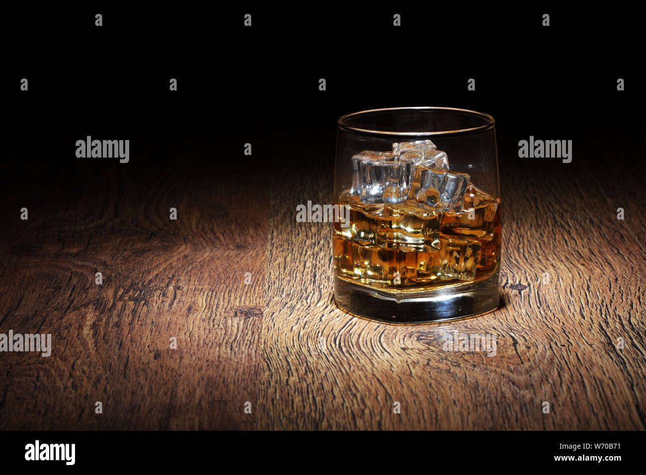 Einen Scotch in Glas tumbler mit Eis Felsen auf altem Holz Oberfläche Stockfoto