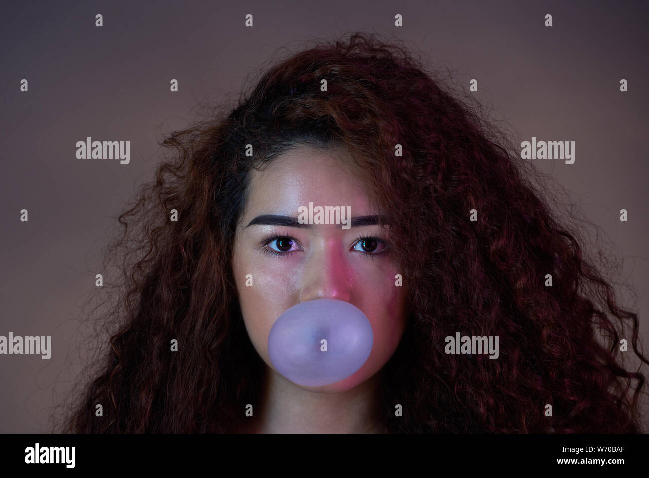 Close-up Portrait von Mädchen mit Bubble gum Ball auf farbigen Hintergrund Stockfoto