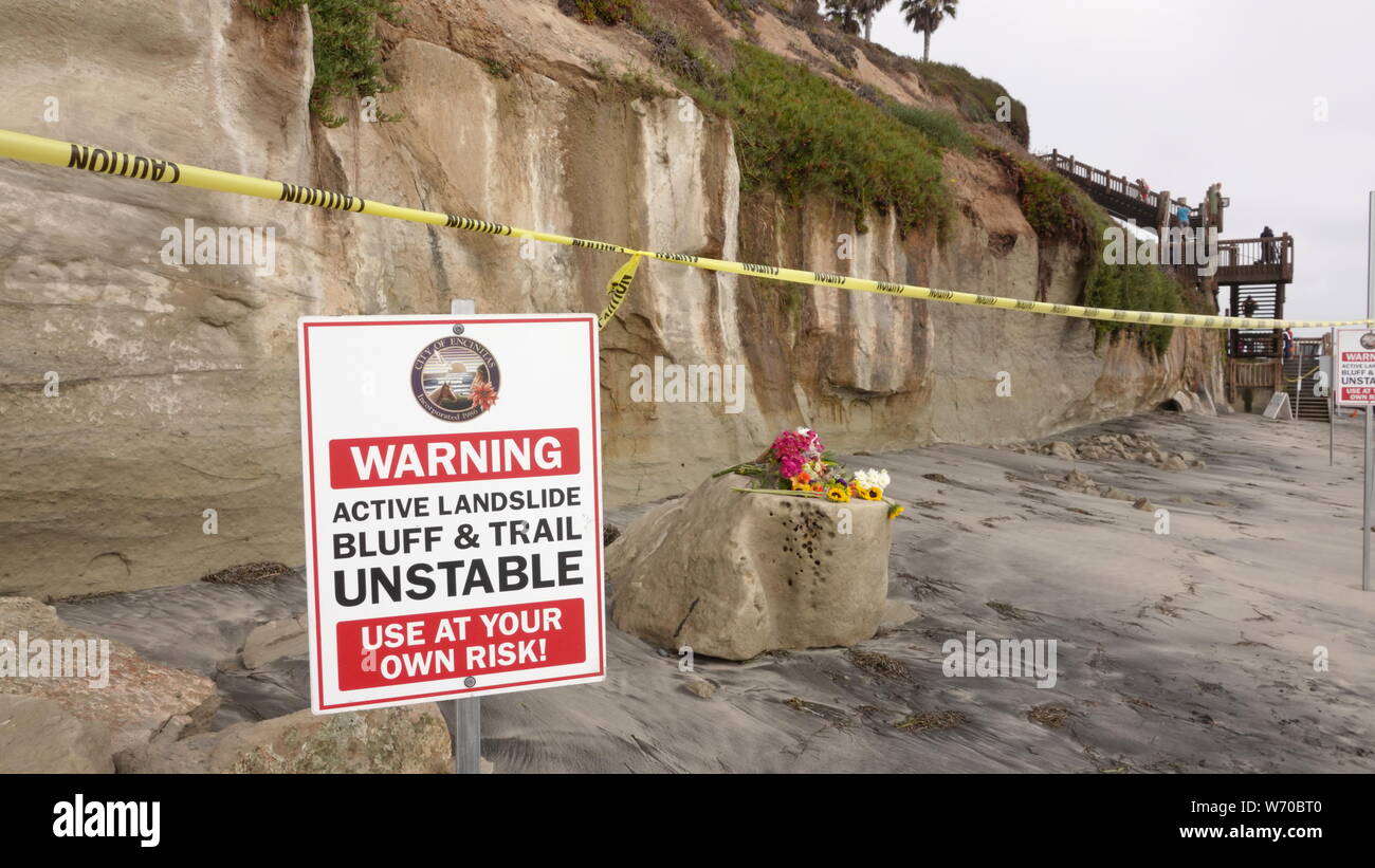Zeichen und Vorsicht Band warnen vor instabilen Klippen am Grandview Strand in Encinitas - eine tödliche Täuschung zusammenbrechen. Blumen trauern um den Strandbesuchern getötet. Stockfoto