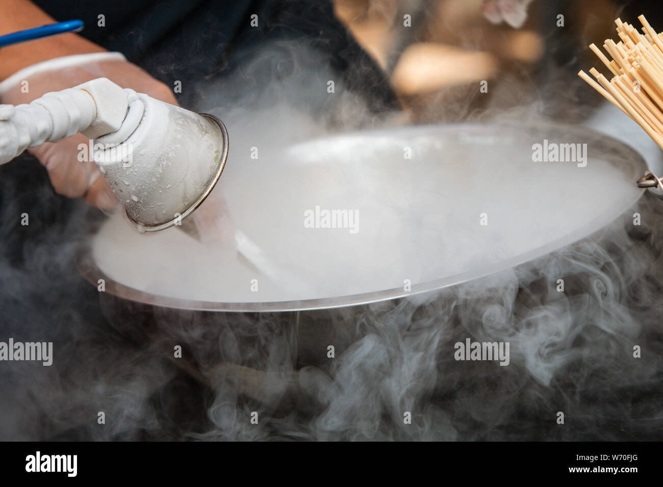 Hand mischt flüssiger Stickstoff mit anderen Zutaten in eine Schüssel geben eine gefrorene behandeln in einem Atlanta Festival zu machen. Stockfoto