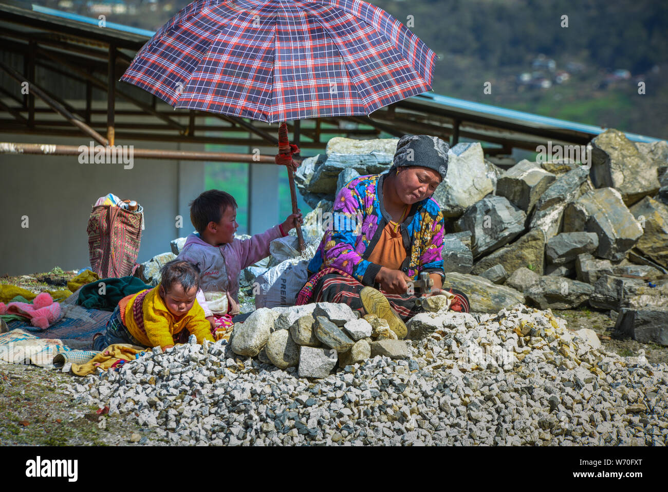 Mutter verdiente sich schwer, sich um ihre Kinder im Beschäftigungsprogramm im Bundesstaat North Hill, Sikkim, Indien, zu kümmern. Stockfoto