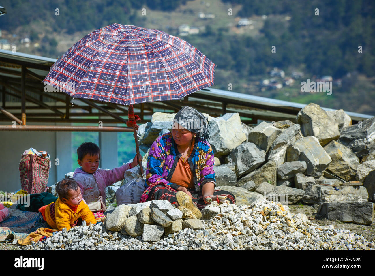 Mutter verdiente sich schwer, sich um ihre Kinder im Beschäftigungsprogramm im Bundesstaat North Hill, Sikkim, Indien, zu kümmern. Stockfoto