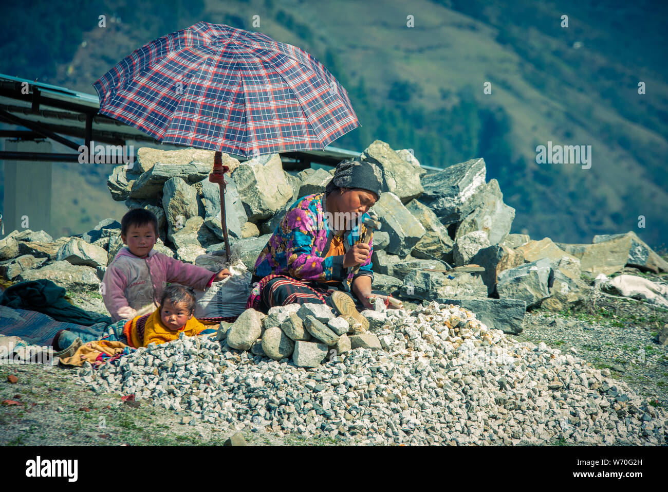 Mutter verdiente sich schwer, sich um ihre Kinder im Beschäftigungsprogramm im Bundesstaat North Hill, Sikkim, Indien, zu kümmern. Stockfoto