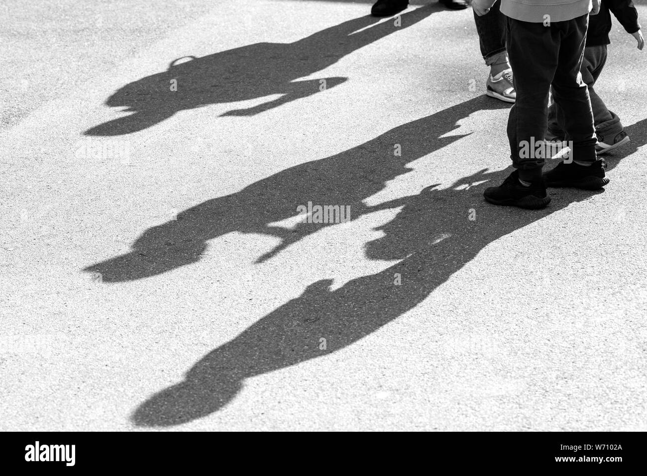 Schatten und Silhouetten von drei Kinder beim Spielen in einer Straße auf der Oberfläche der asphaltierten Straße als Hintergrund- oder Textur Stockfoto