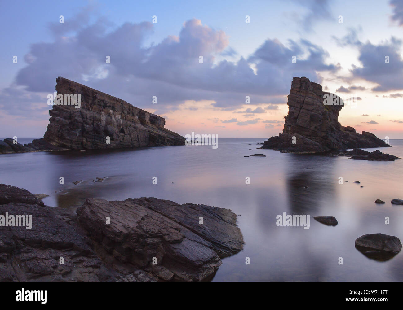 Felsen im Wasser in der Nähe der Küste, die zum Zeitpunkt des Sonnenaufgangs Stockfoto