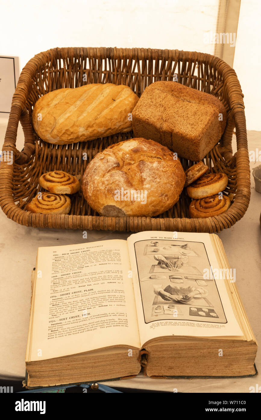 Mrs Beeton's Book von Haushalts-, eine alte oder traditionelle Kochbuch, neben einen Korb mit Brot zu einem County zeigen, Großbritannien Stockfoto