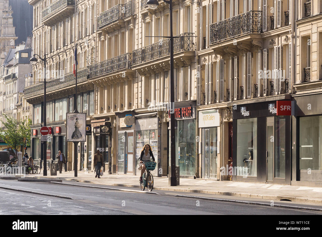 Paris Street Frau Radfahren - Morgen street scene in der Rue de Rivoli im Marais-Viertel von Paris, Frankreich, Europa. Stockfoto
