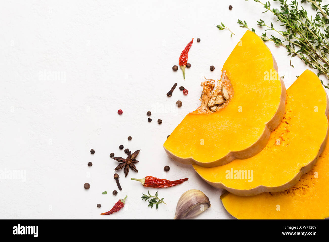 Scheiben der Reife Kürbis mit Gewürzen und Olivenöl. Gemüse Zutaten zum Kochen. Herbst essen Konzept. Stockfoto