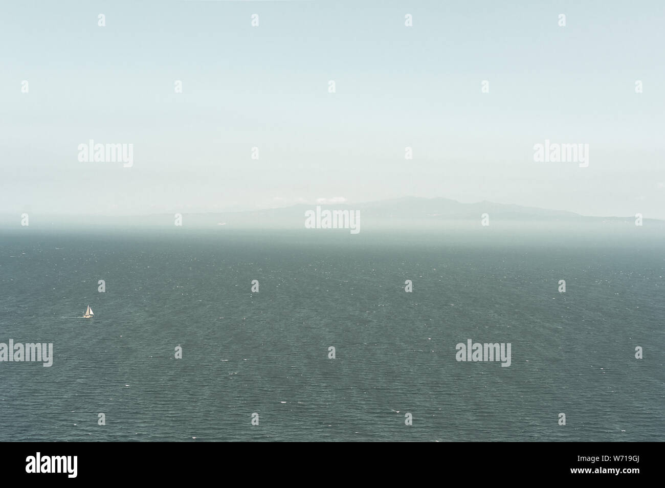 Landschaft einer unendlichen Meer und Himmel mit einem kleinen Segelboot während einer nebligen und trüben Tag. Hintergrund der schönen Meer mit großen kopieren. Stockfoto