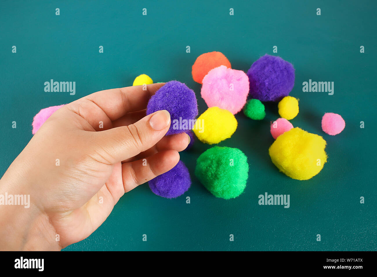 Hand berührt eine weiche Wolle pompom. Das Konzept der Touch, Taktilität, Gefühle. Stockfoto