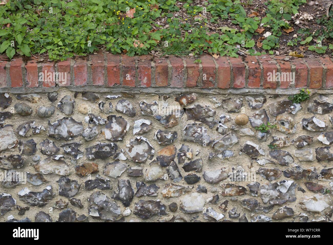 Grau Flint stone wall gekrönt mit Ziegel Stockfoto