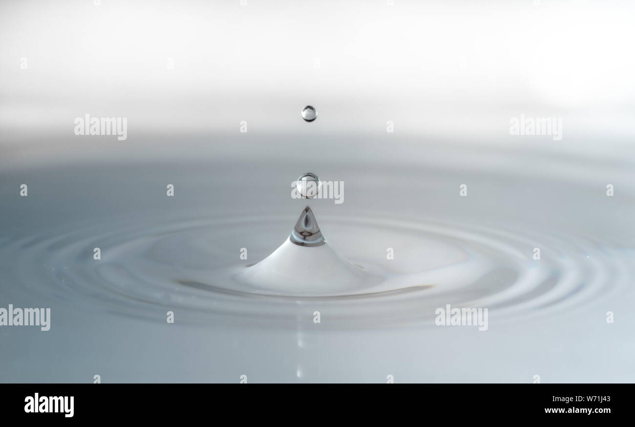 Einen Wassertropfen auf einem weißen Hintergrund heraus springen und die Aufteilung in zwei. Stockfoto