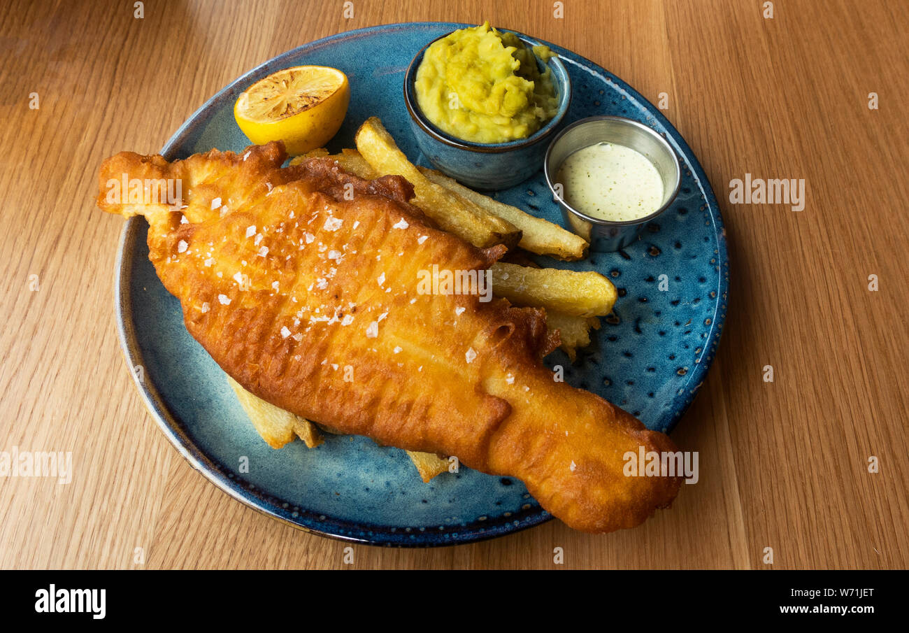 Fisch und Chips mit Erbsenpüree und Zitrone Stockfoto