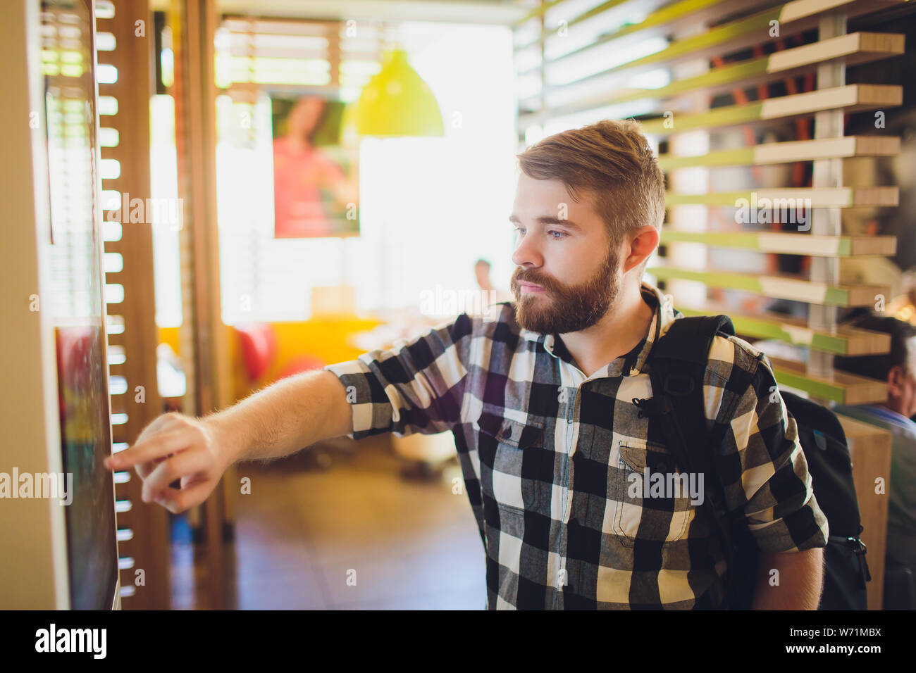 Ein Mann Bestellungen Essen im Touch Screen Terminal mit elektronischen Menü in Fast Food Restaurant. Stockfoto