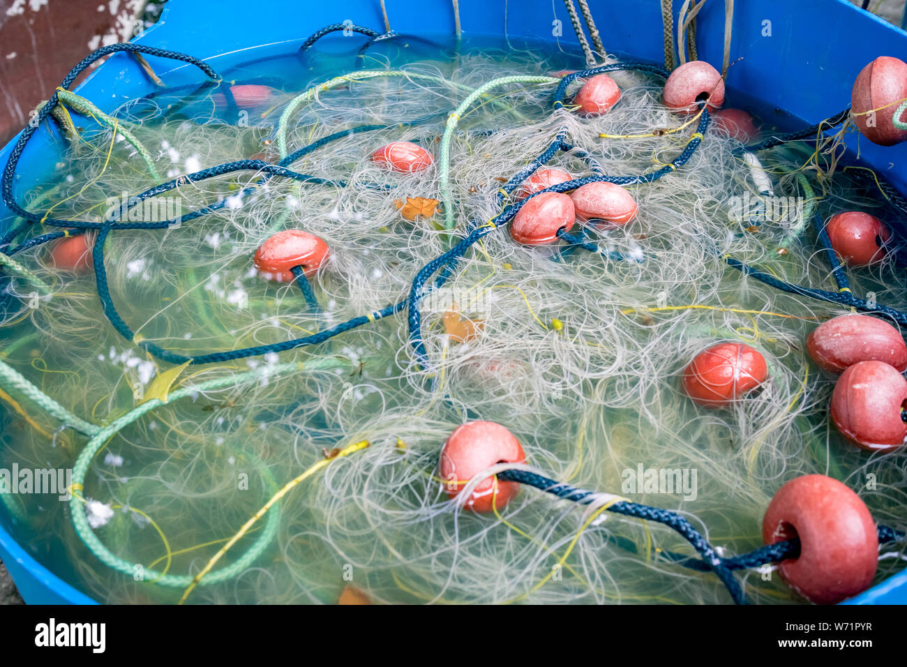 Selektiver Fokus Nahaufnahme der Fischernetz versunkenen in Blau gebrochen alte Wasser barrel. Marine Hintergrund, Foto auf der Insel von Ioannina, Griechenland Stockfoto